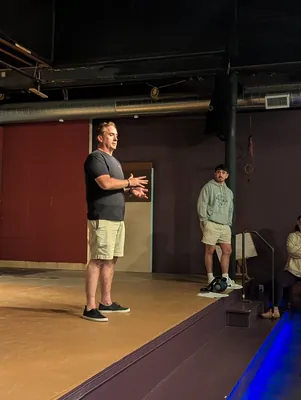 A director working with a student on the empty stage