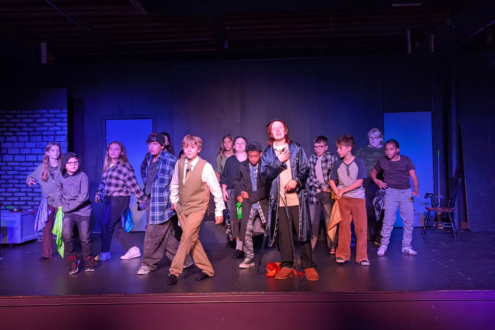 The company of Oliver! The Musical under stage lights