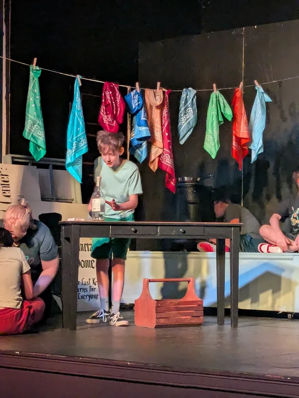 A student performing on the laundry line set of Oliver! The Musical