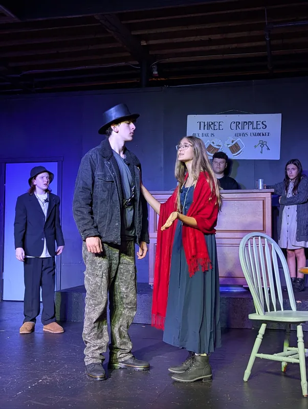 A tavern scene from Oliver! The Musical with the company on stage