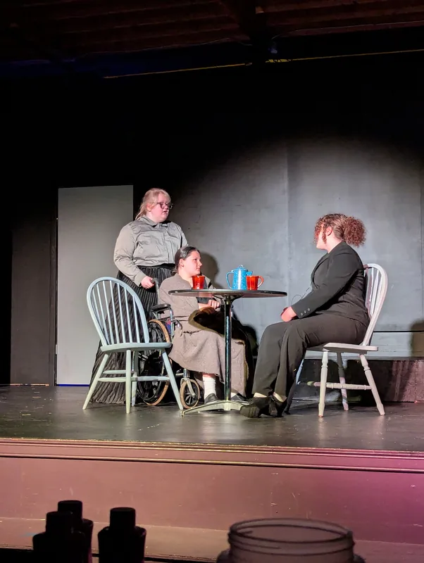 A quiet scene at a table in Oliver! The Musical