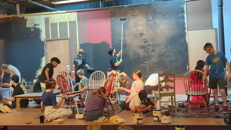 Students painting chairs and scenery during build week